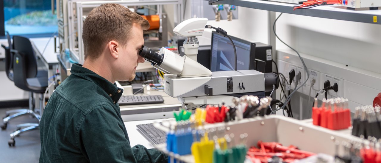 Nanomagnetic Devices: Studierender untersucht Proben mit Mikroskop, um Herstellungsqualität zu überprüfen und dokumentieren.